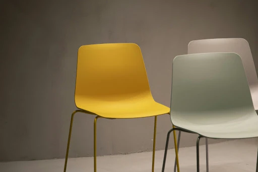 a set of simple chairs accented by a single bright yellow chair